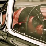 A close-up of the outside of an older collectible Corvette. The windows aren't tinted, and the inside of the car is red.