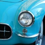 Front view of a classic turquoise car, showing a chrome bumper, circular headlight, and glossy bodywork.