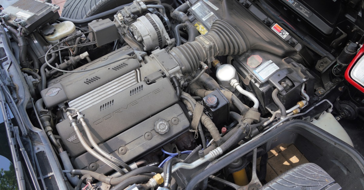 Open Corvette engine bay showing the engine, air intake, alternator, hoses, wiring, and other mechanical parts.